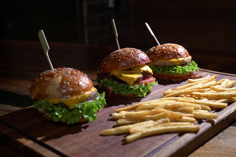 Burgers au cheddar et frites servis sur une planche en bois.