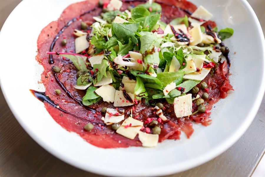 Carpaccio de bœuf avec roquette, copeaux de parmesan et filet de crème de balsamique.