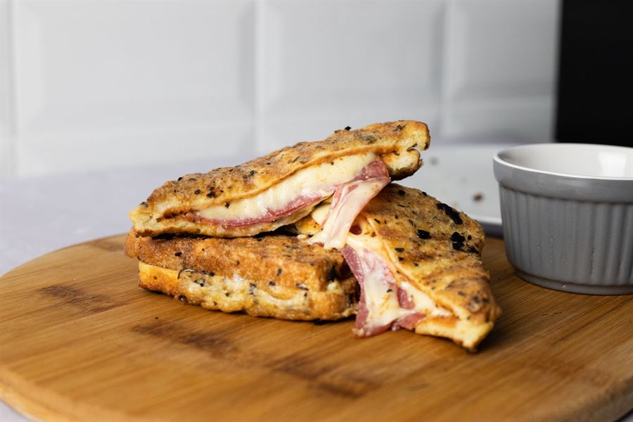 Croque-monsieur au jambon et au fromage, tranché sur une planche en bois.