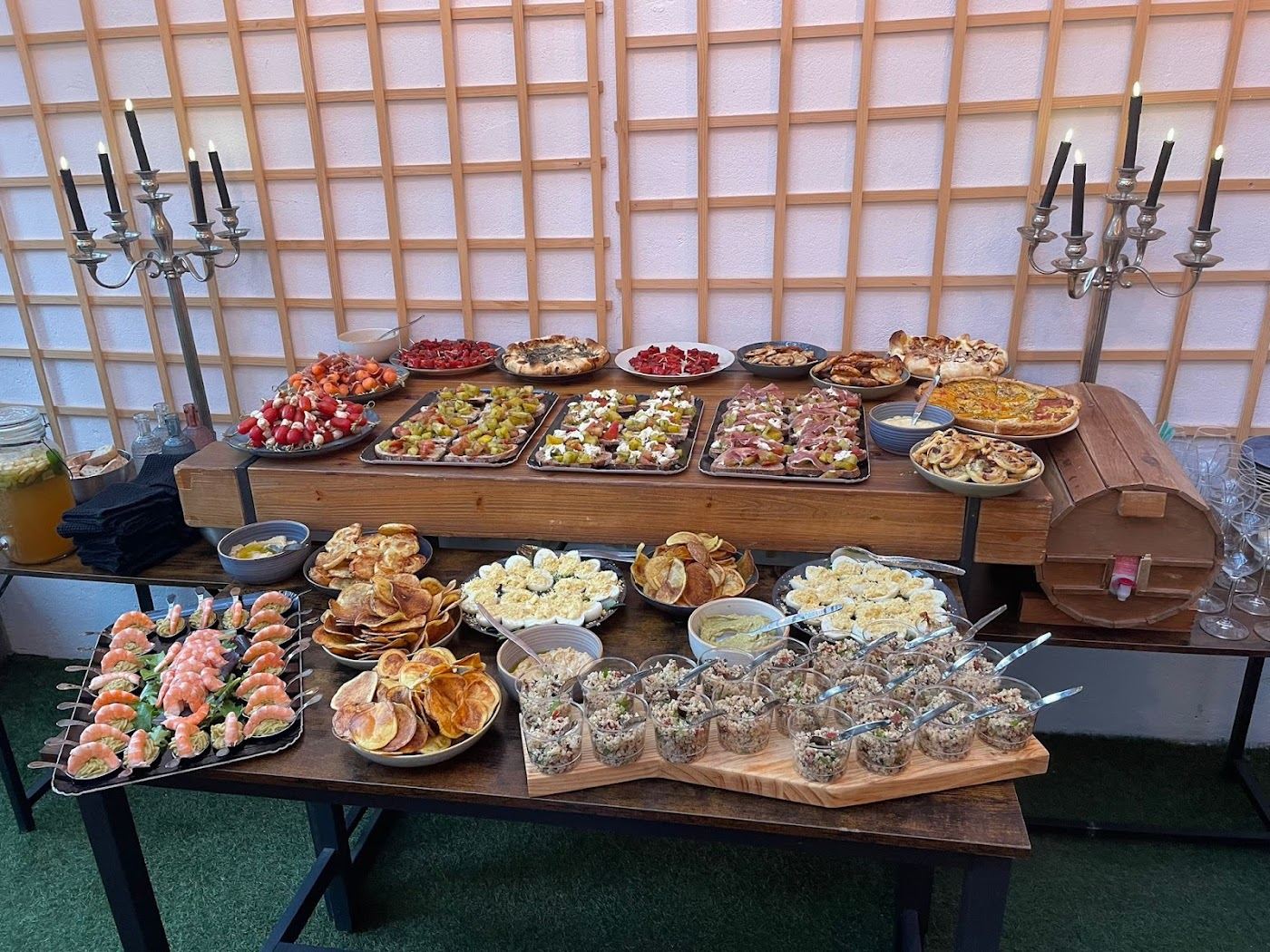 Buffet traiteur : planches de charcuterie, verrines, toasts et plateaux sur une table en bois.
