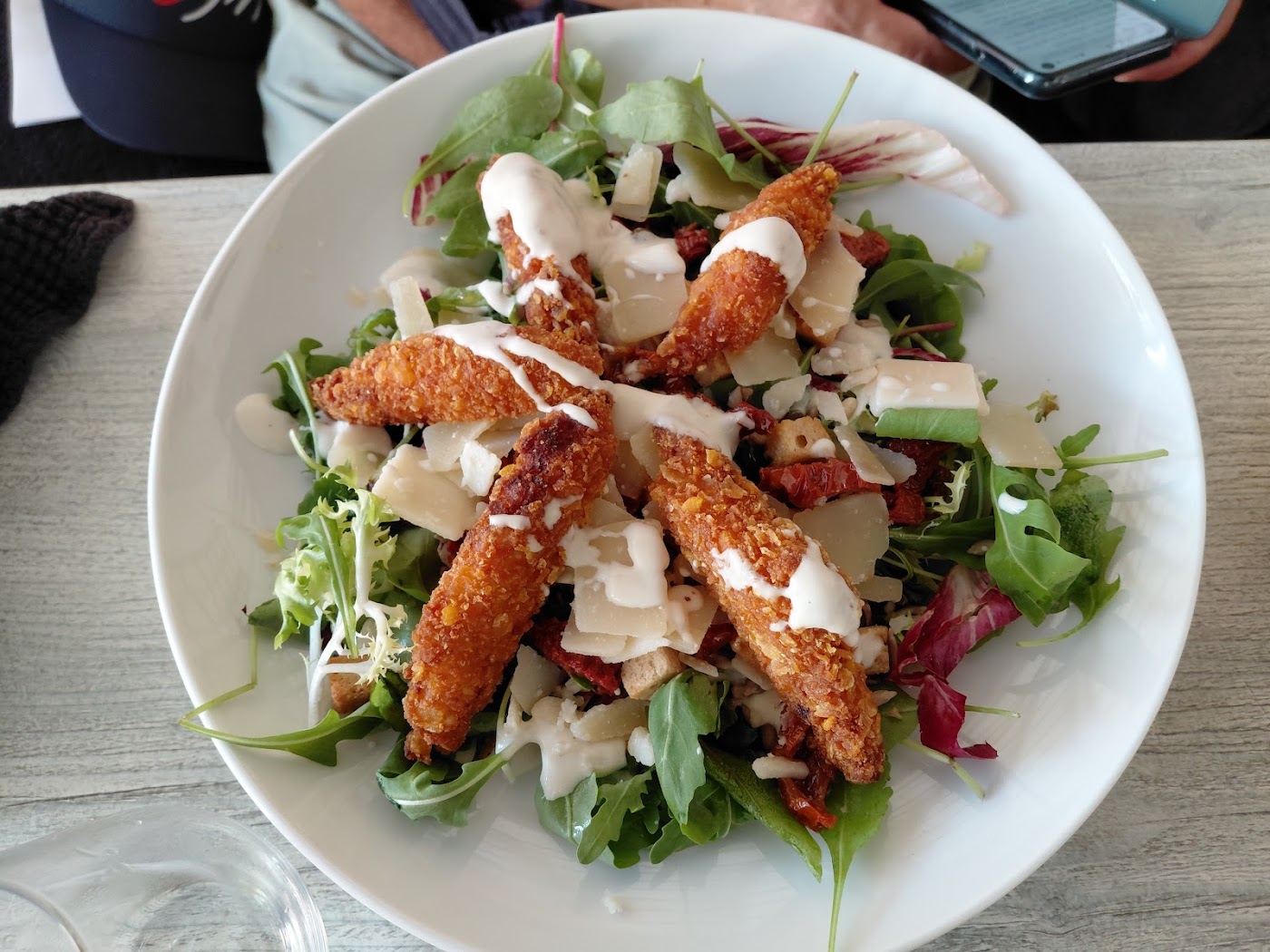 Salade César au poulet pané, copeaux de parmesan et roquette.