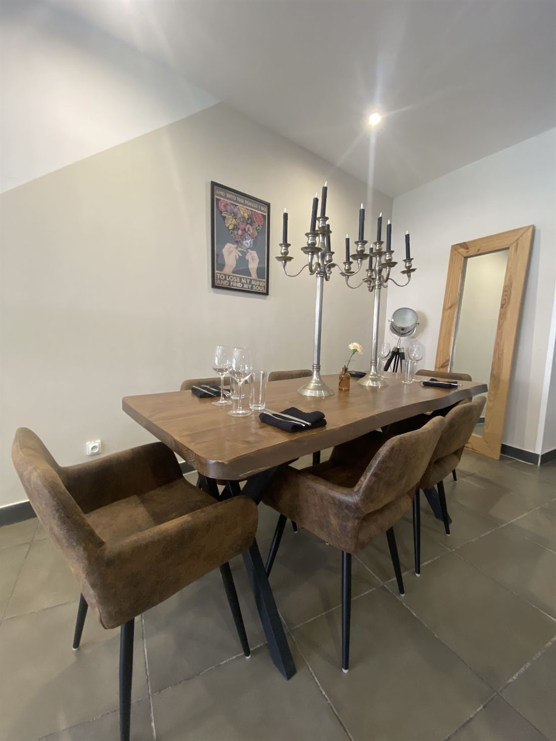 Grande table en bois avec chandelier et chaises en velours dans la salle du restaurant.